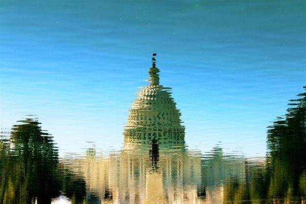 The U.S. Capitol dome is reflected in a shimmering pool of water.