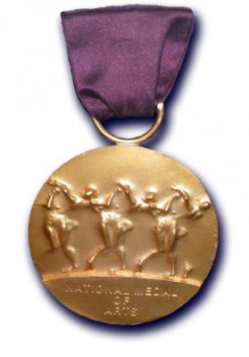 The National Medal of Arts, round and gold in color with embossed design and a purple ribbon.