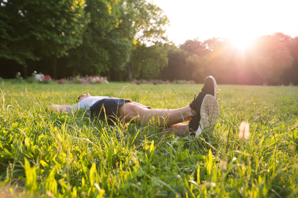 A young man relaxing in the sunset and lying in the grass.