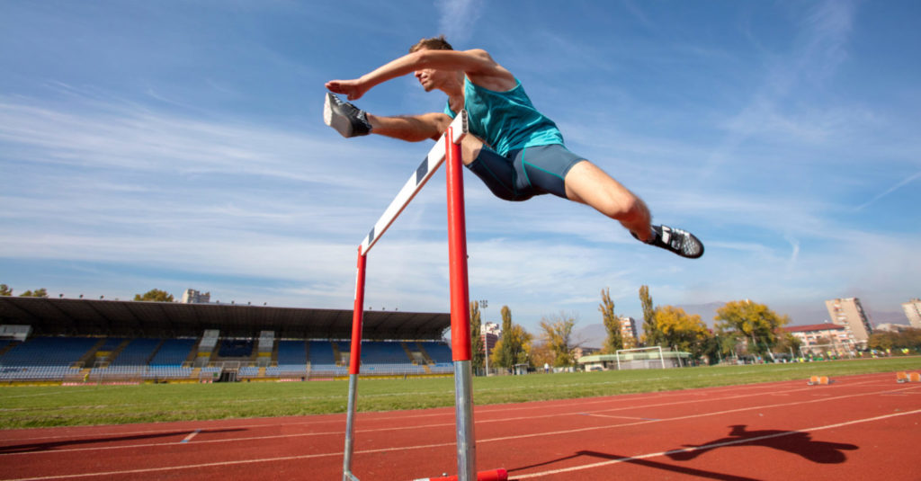 Low angle view of determined male athlete jumping over a hurdles.