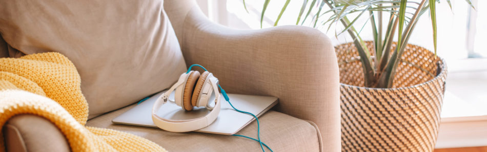 Headphones lying on laptop on armchair. Hygge minimalist home room indoor apartment interior decoration. Cozy room in natural tone