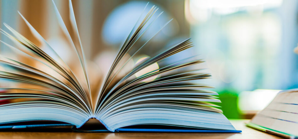 Open book lying on the table in the public library with pages fanning out