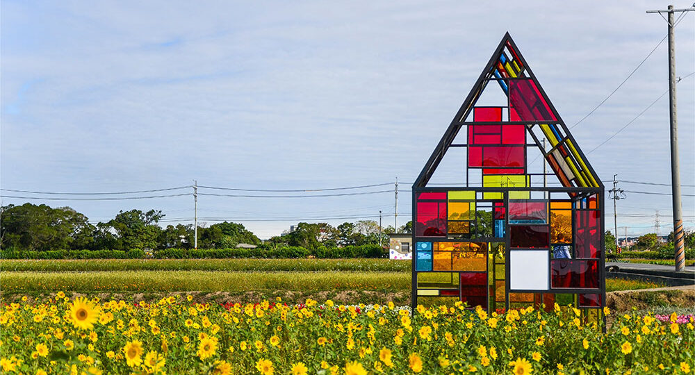 Purely decorative stock art of a field of yellow wildflowers and a structure resembling an A-frame house without walls and stained glass of different colors