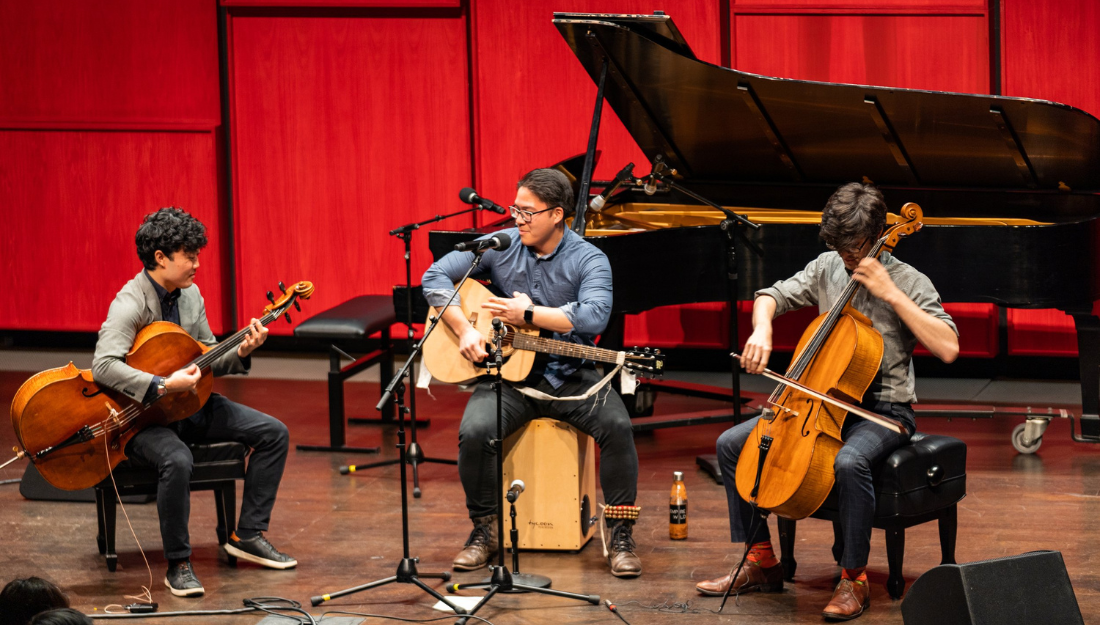 casually-dressed members of the musical trio Empire Wild perform on a simple concert stage