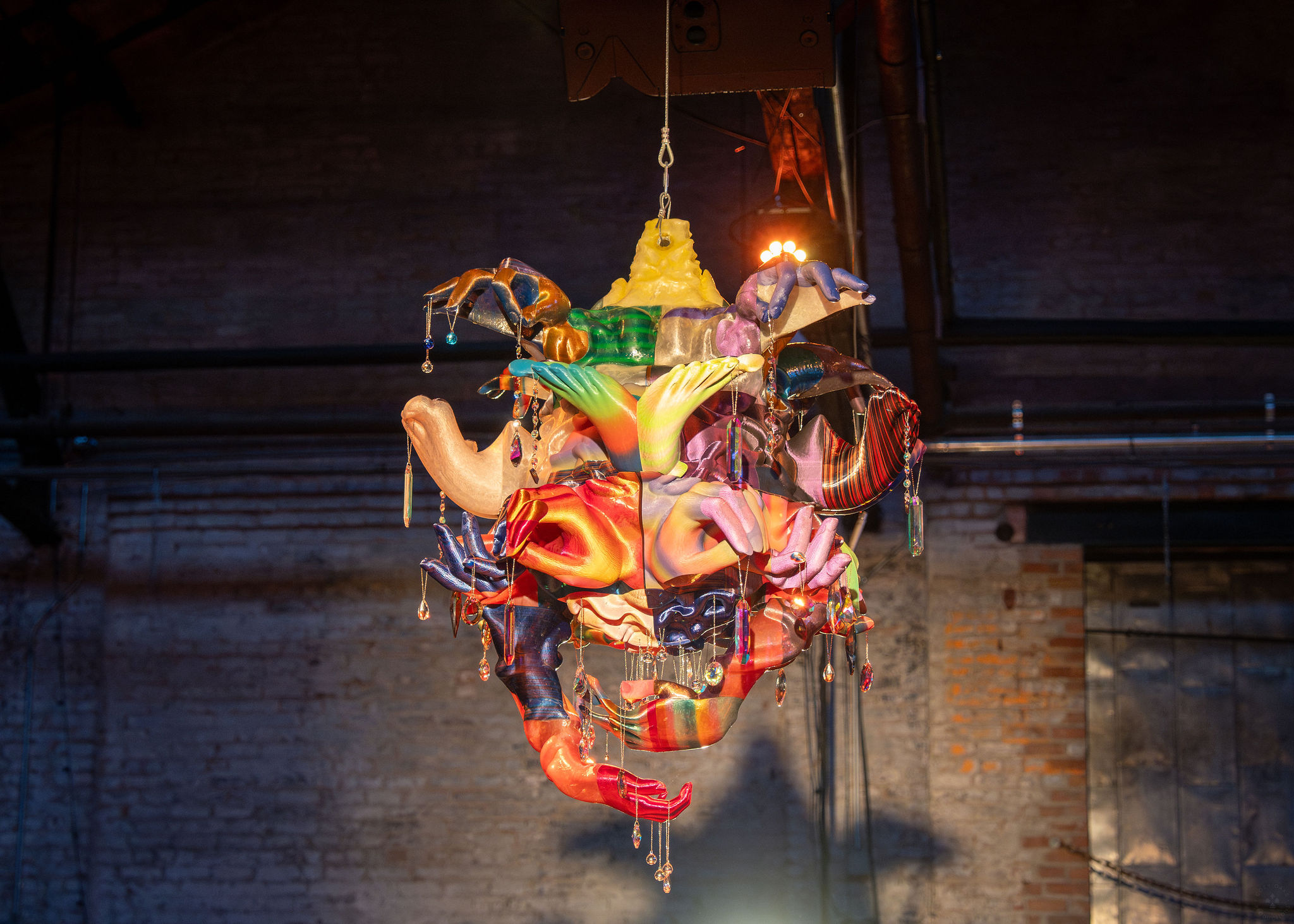 colorful 3 dimensional hanging artwork appears to feature hands and feet in various angles, accented by beading