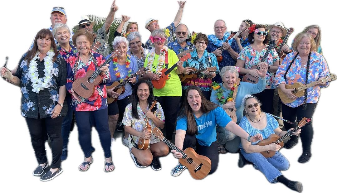 a group of smiling musicians wearing floral shirts and costume pieces, holding their ukuleles