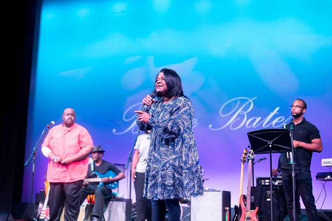 Bessie Bates, a Black woman, sings onstage with other Black musicians