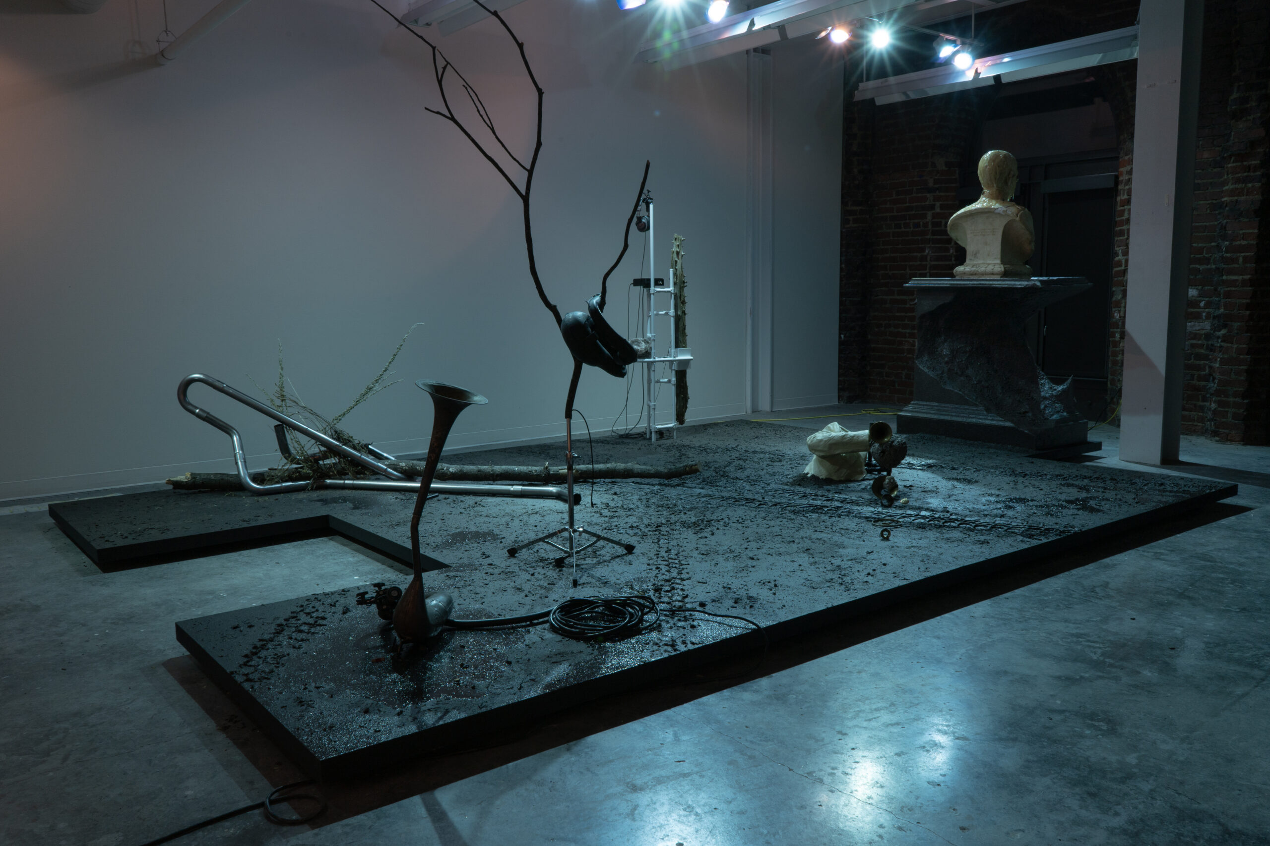 A darkly lit blue room contains work from Michael Webster's installation, Sonic Fictions.