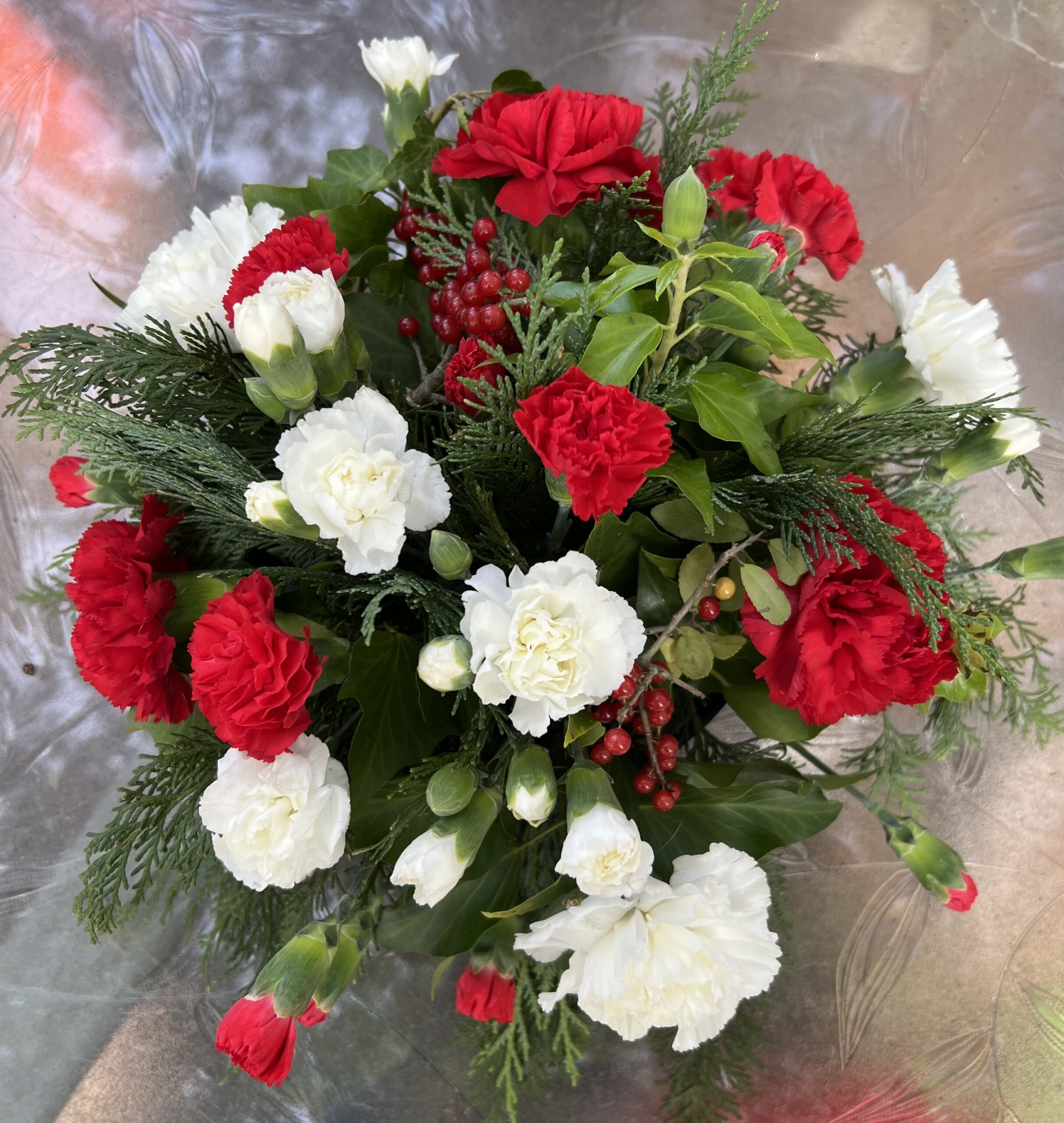 a bouquet of red and white carnations and greenery