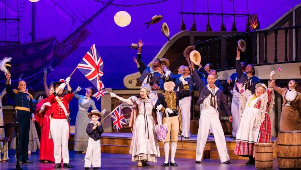 Actors in 19th century costumes perform on a stage ship.