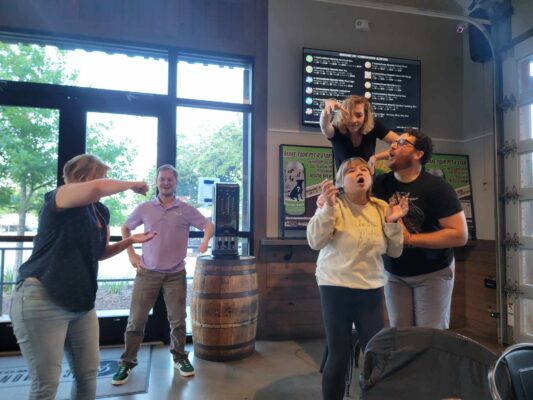 Five people play out an improv scene in a coffee shop.