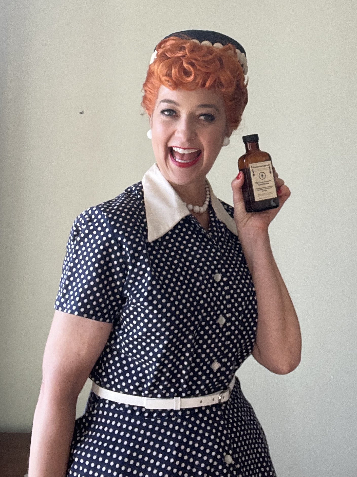 An actress costumed as Lucille Ball, holding a bottle of Vitameatavegamin tonic.