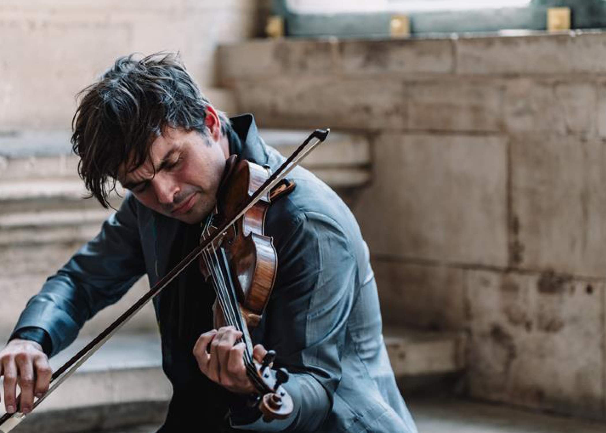 Violinist Francisco Fullana has dark hair and wears a jacket as he plays in a stone room.