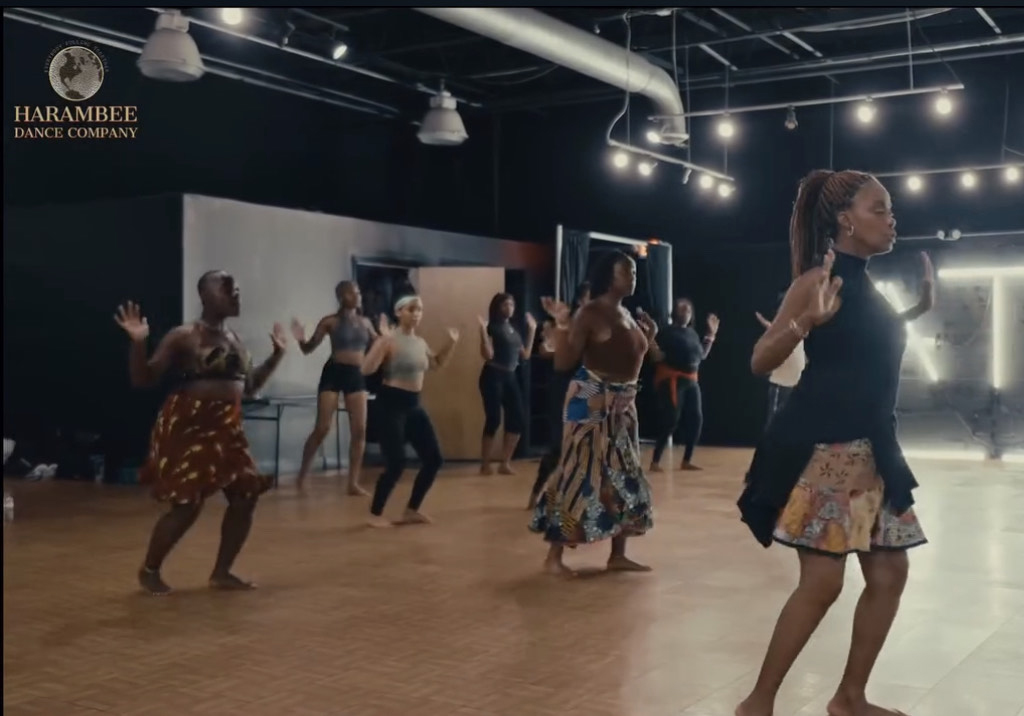 A group of BIPOC individuals, primarily women, in a studio dance class, dancing barefoot.
