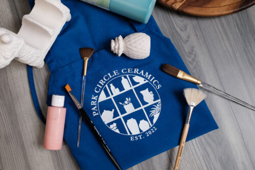 A blue apron with the logo of Park Circle Ceramics.
