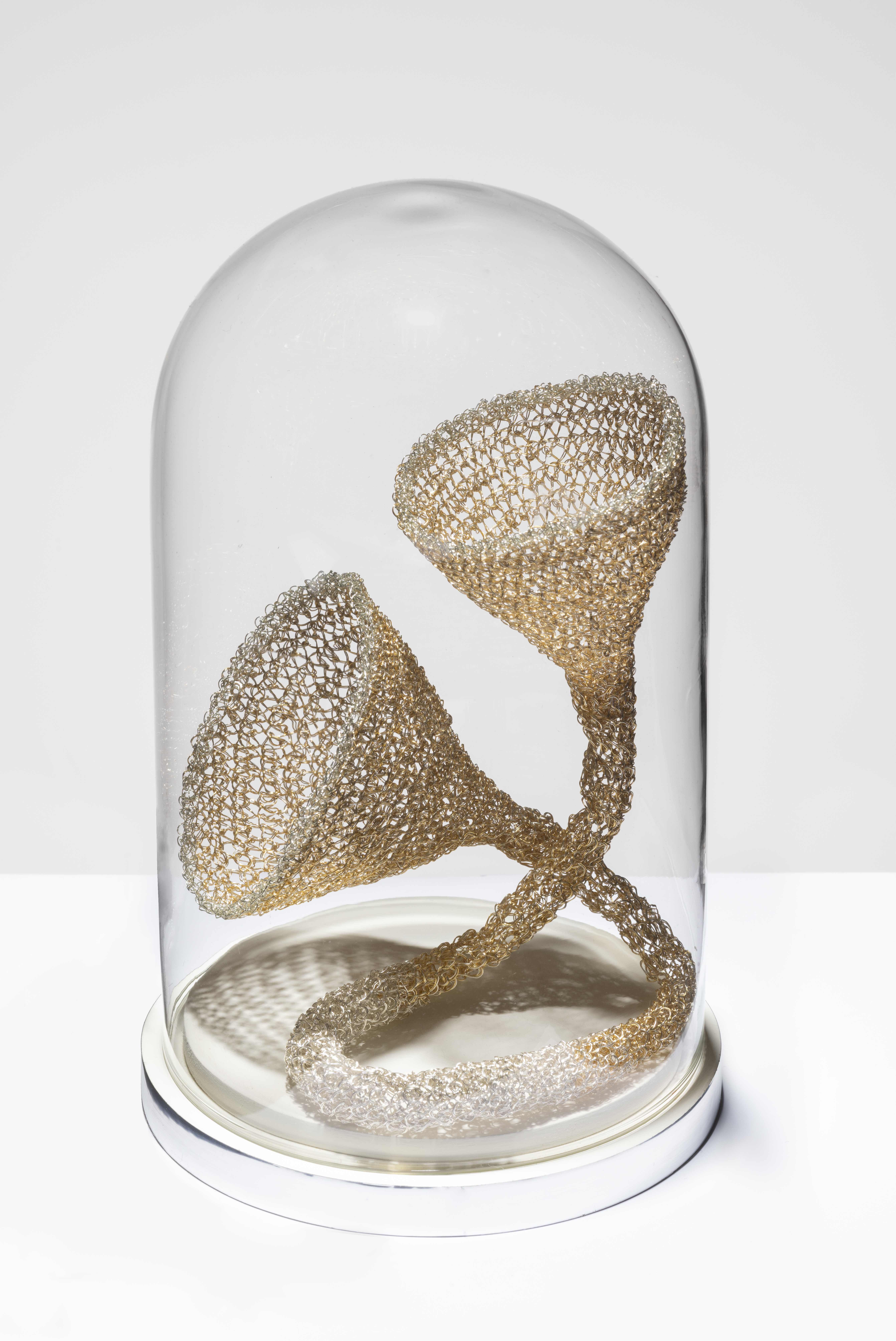 Sculptural tube forming a cone on each end, crocheted of copper wire, encased in a glass dome.