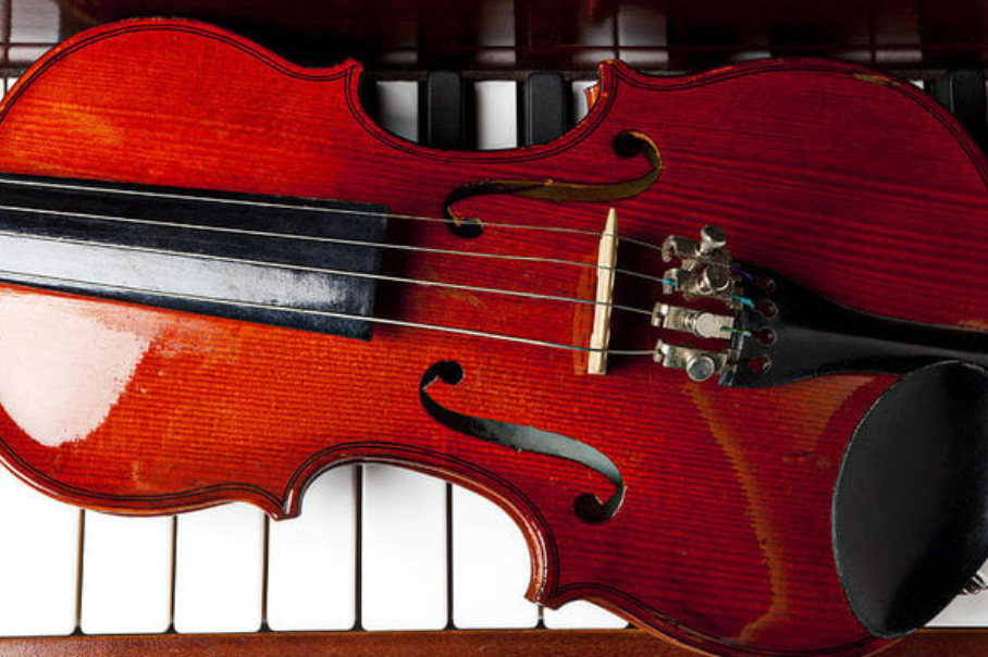 A violin lying on a piano keyboard.