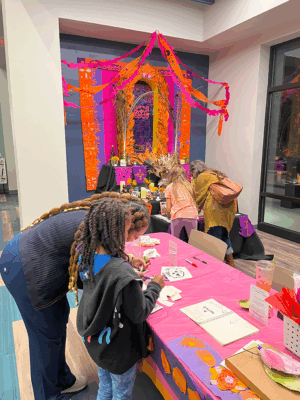 Two BIPOC females, one young and one adult, using a work surface in a an art workshop.