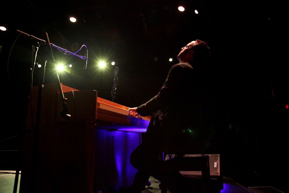 A man plays piano onstage. He sits in profile with head thrown back.
