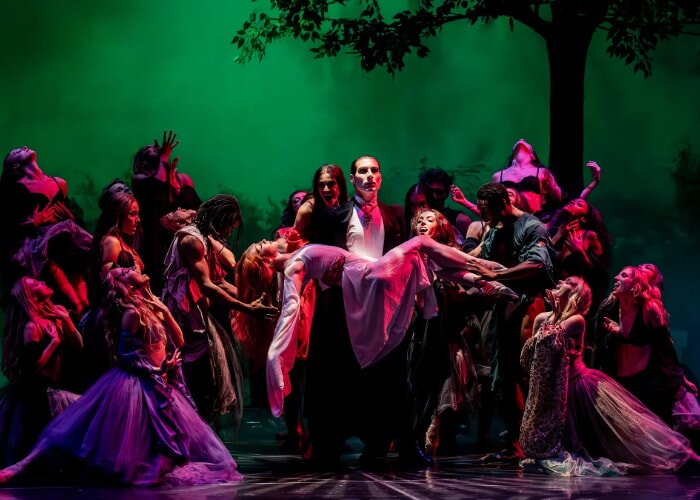 Ballet dancers depict a night scene of Dracula holding an unconscious woman, surrounded by vampires.
