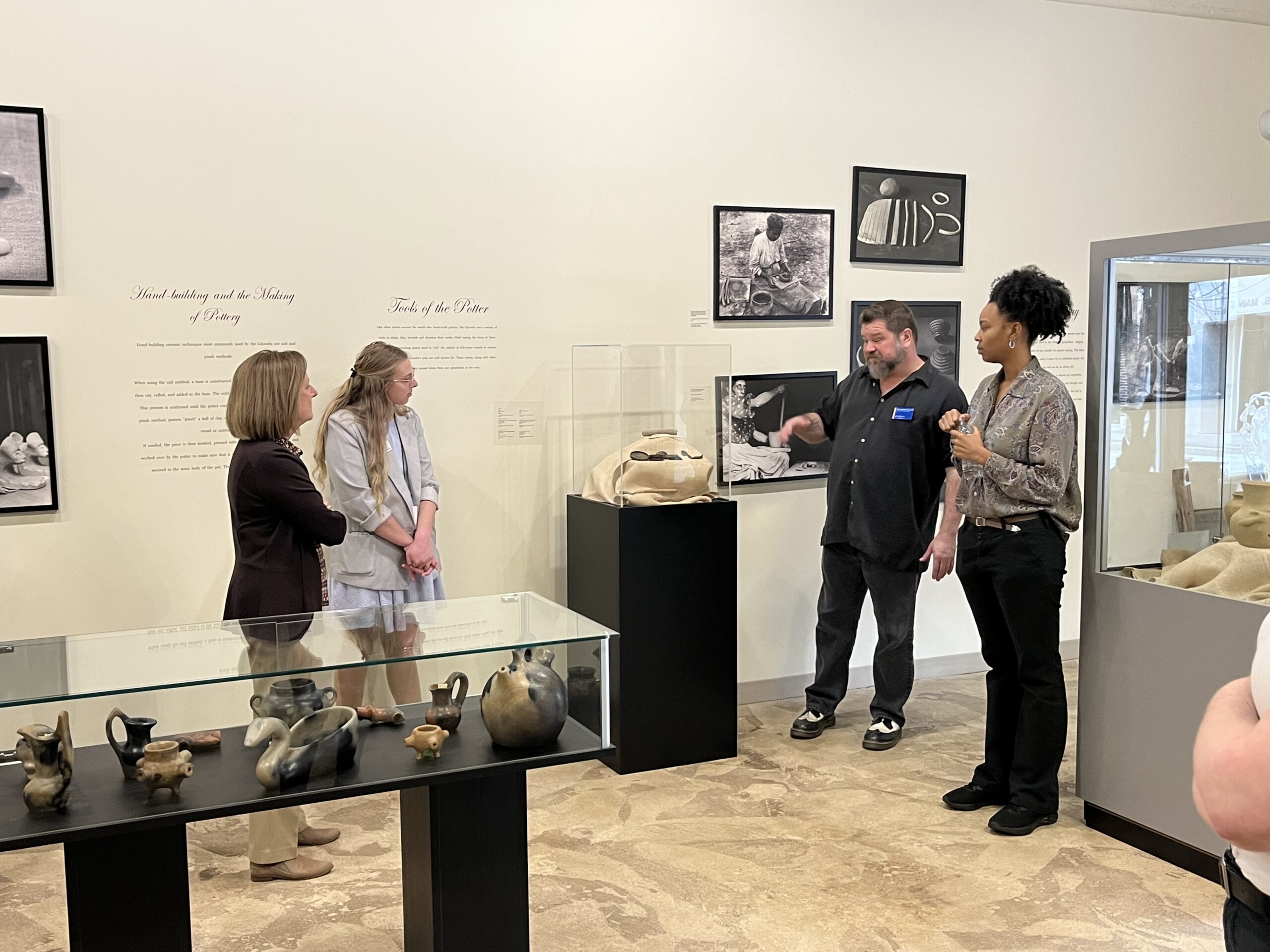 A bearded man explains objects in a gallery of Native American artwork.