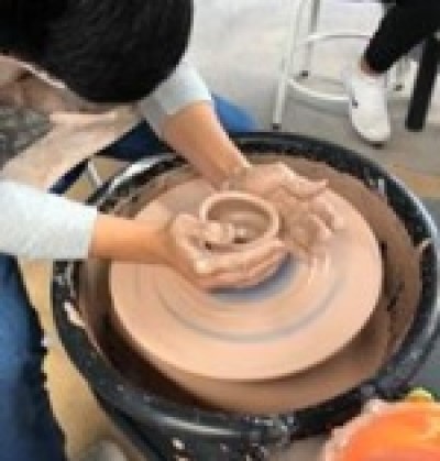 A person works on a pottery wheel.