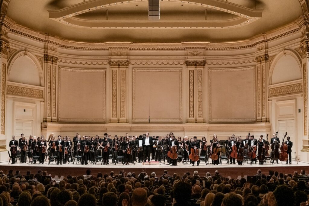 The College of Charleston Orchestra stands on stage in concert black attire.