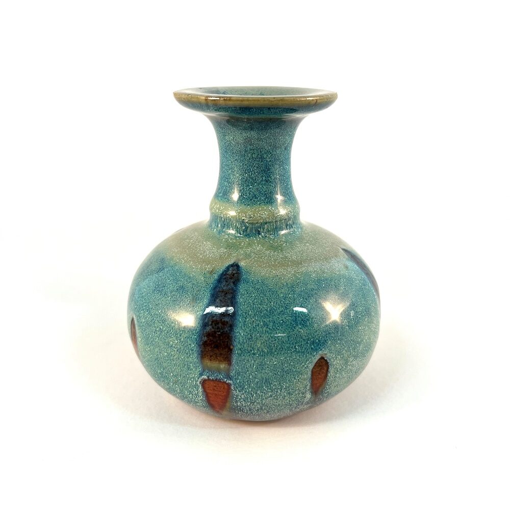 A small, squat, studio art pottery vase with a turquoise, green, and brown drip glaze.
