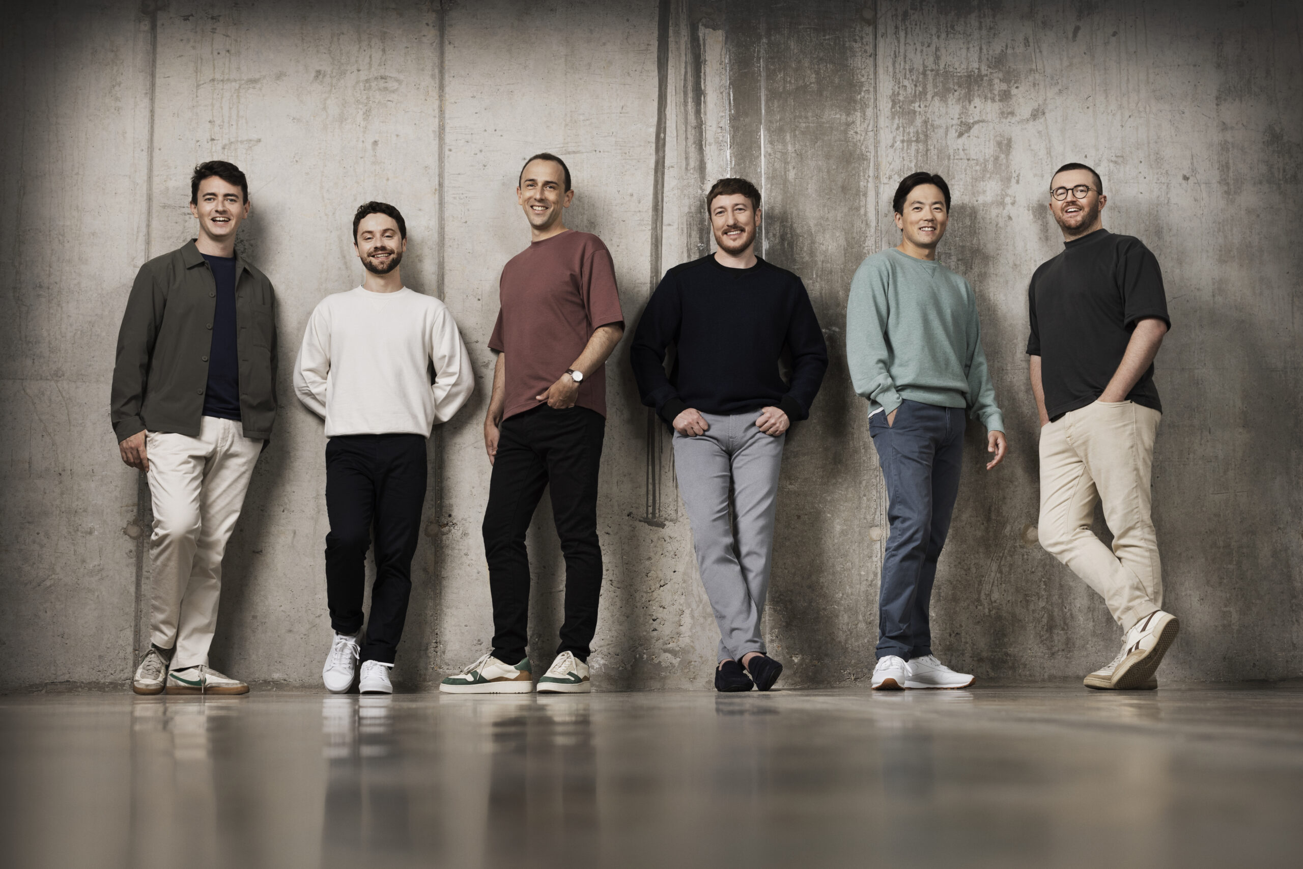 The six members of The King's Singers stand posing against a concrete wall.
