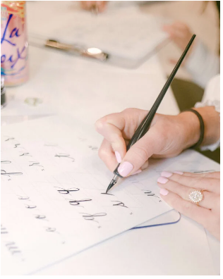 Feminine hands practicing modern pointed-pen calligraphy. It is a serene scene.