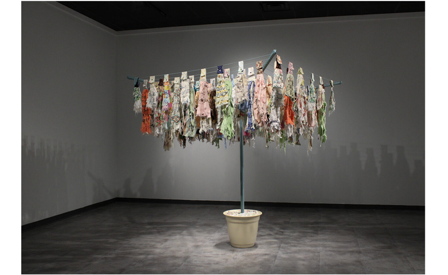 Artwork. An umbrella-style laundry rack holding dozens of rags springs from a large plant pot.