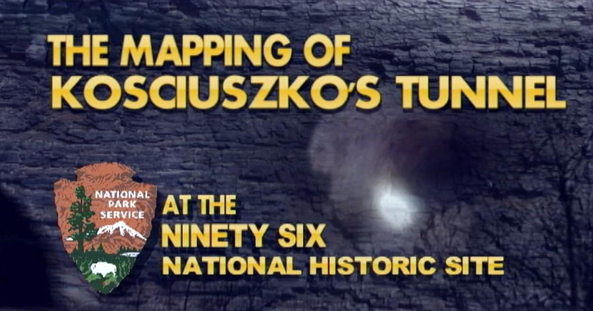 A dark stone wall with a flashlight shining on it. Logo of the National Park Service.