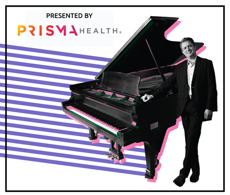 A man in a dark suit stands with a black baby grand piano.