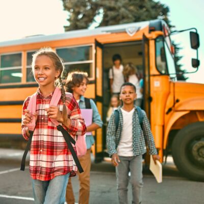 Children departing a school bus on a sunny morning.