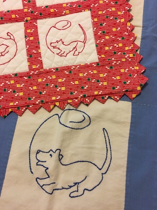 Quilted squares embroidered with a line drawing of a dog chasing a balloon.