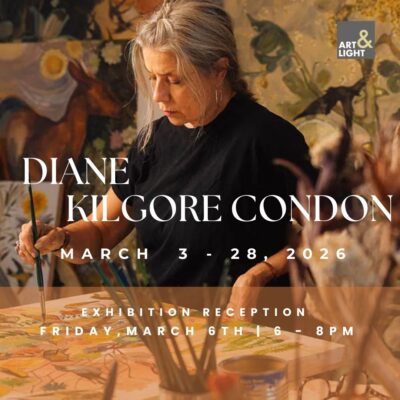 A woman with gray hair paints on a horizontal surface, amid other paintings and art supplies.