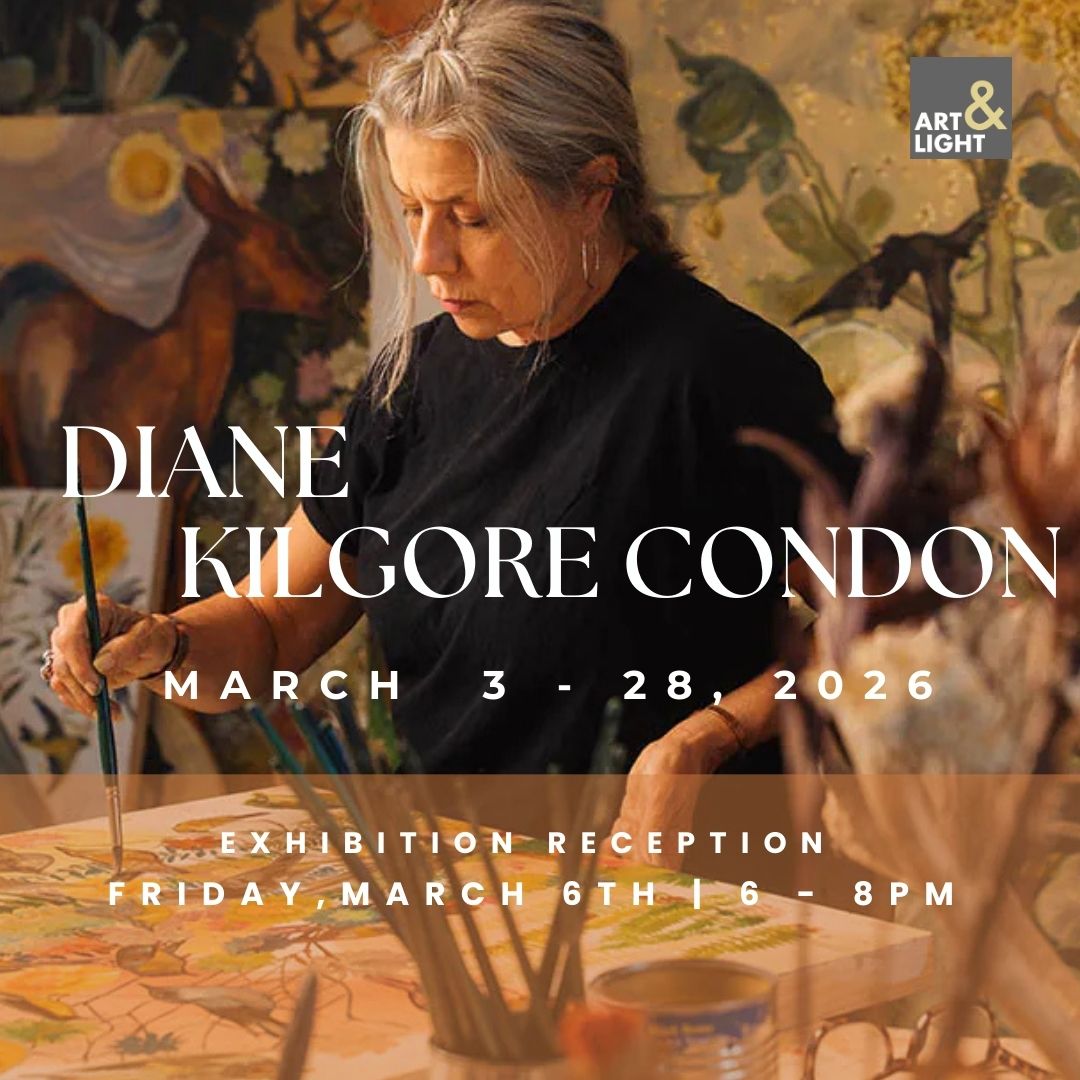 A woman with gray hair paints on a horizontal surface, amid other paintings and art supplies.