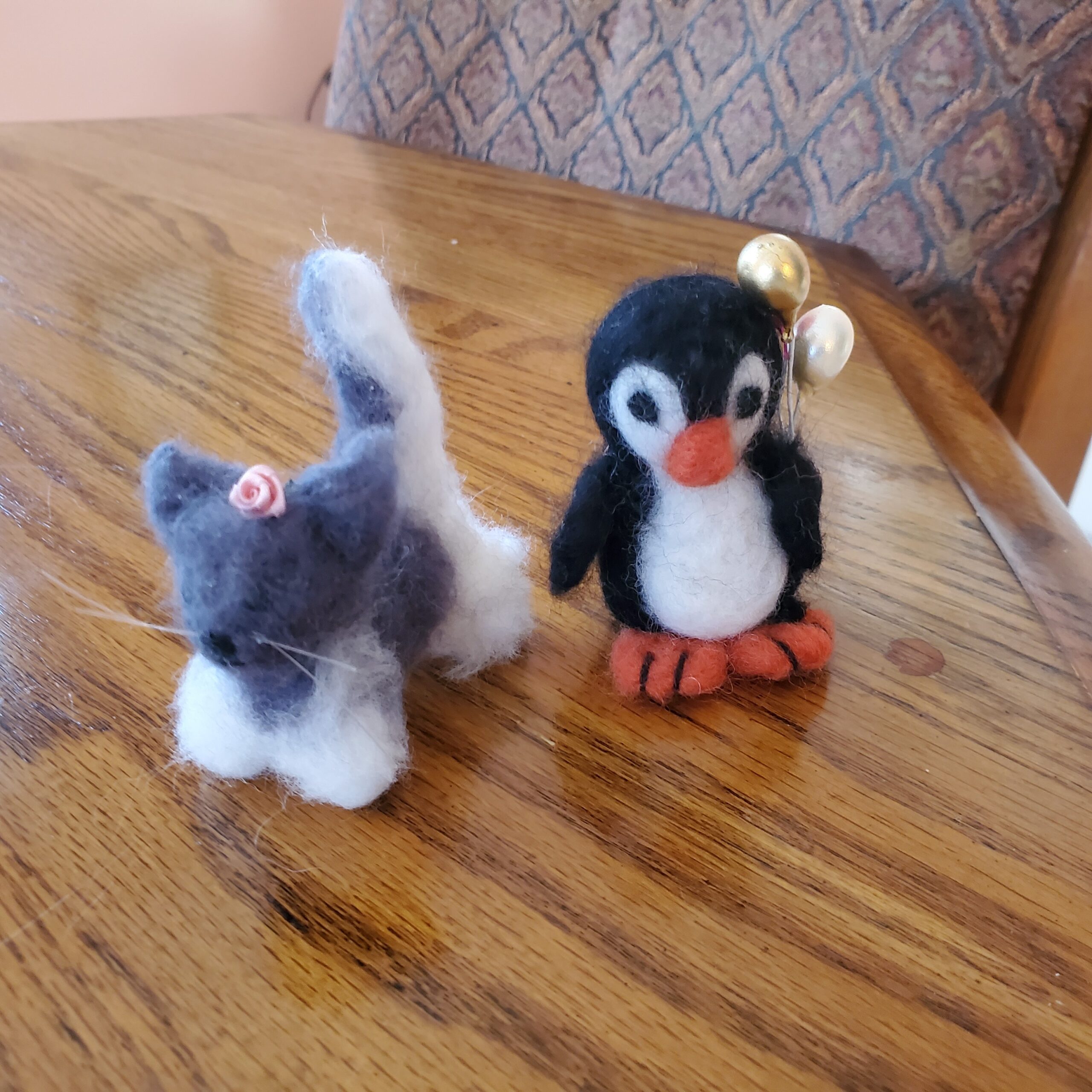 Small animals constructed of felt. One is a gray and white kitten; the other is a penguin.