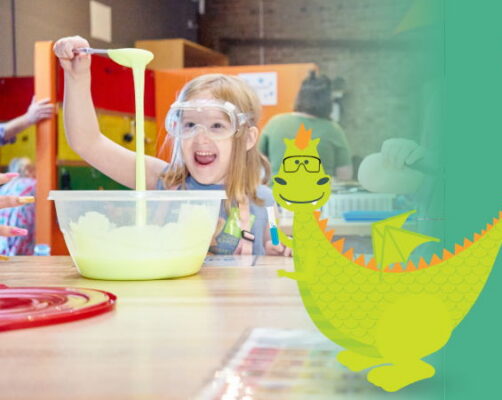 A young student reacts with joy as she watches neon liquid fall from a spoon at a work table.