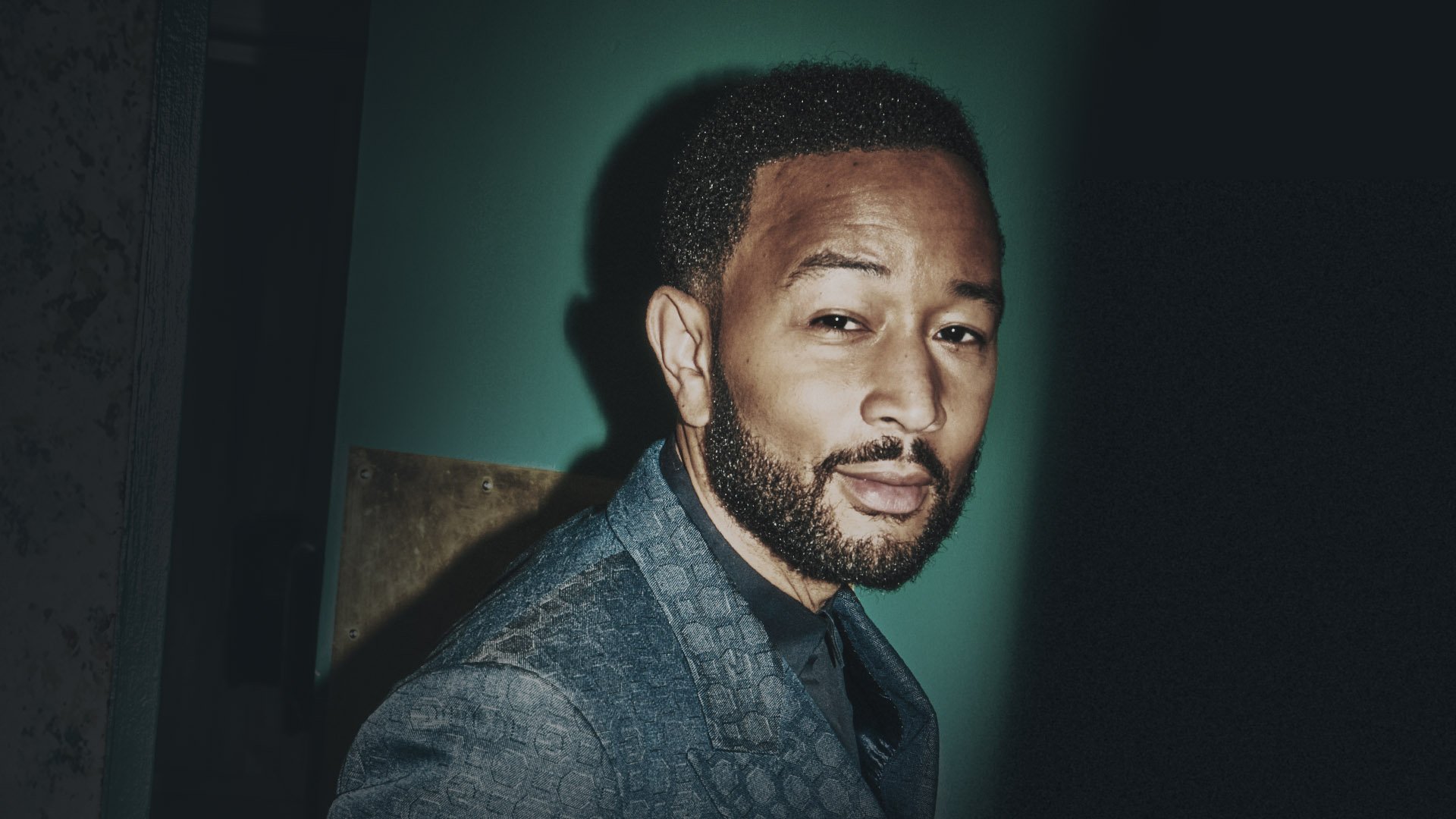 A Black man with facial hair gives a slight smile to the viewer.