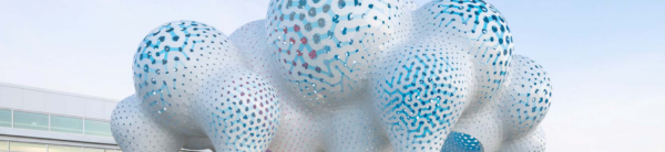 A very large outdoor artwork resembles white balloons with blue designs and perforations.