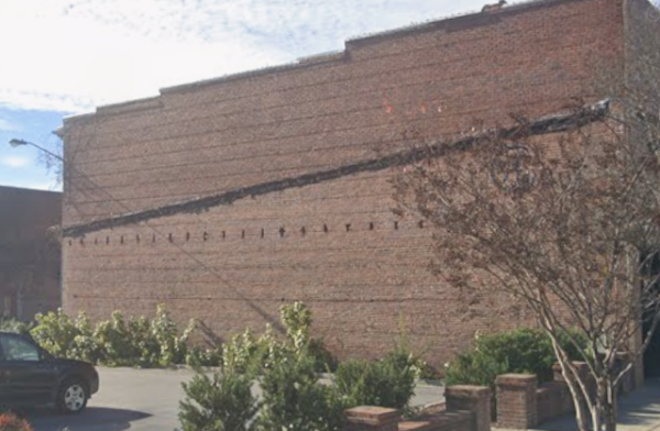 Red brick side of a multi-story building, future site of a mural.