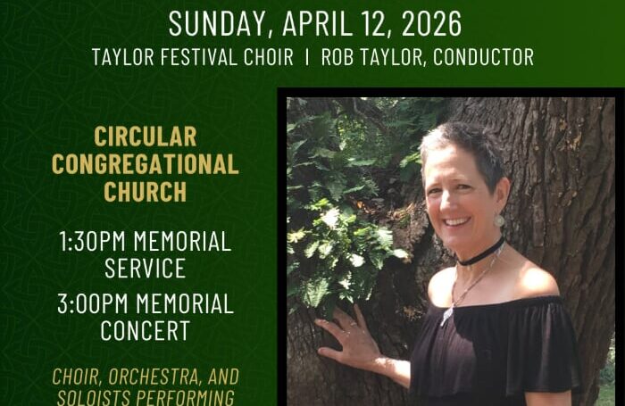 A smiling woman with short graying hair poses by a tree.