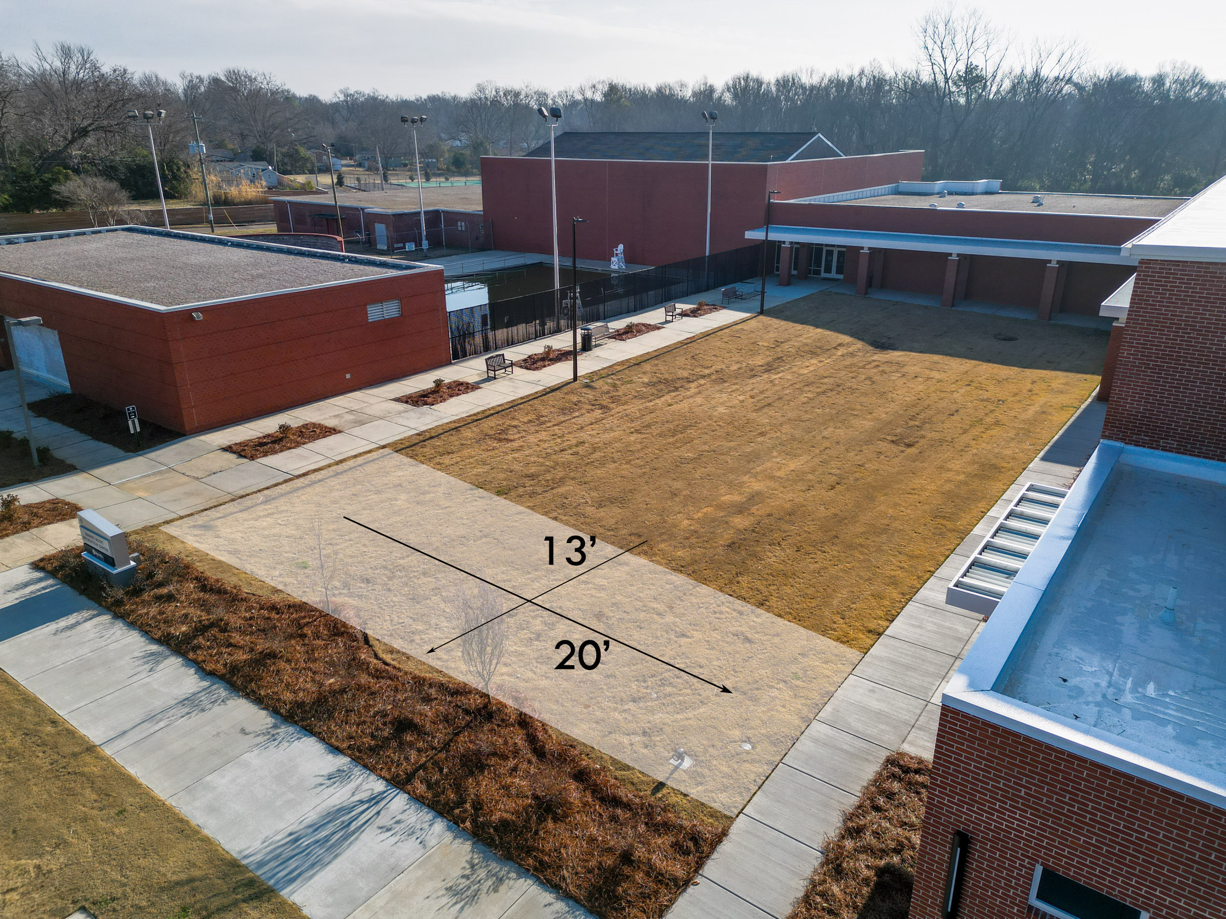 Site of future public art. A 20 foot by 13 foot section of lawn among low brick buildings.