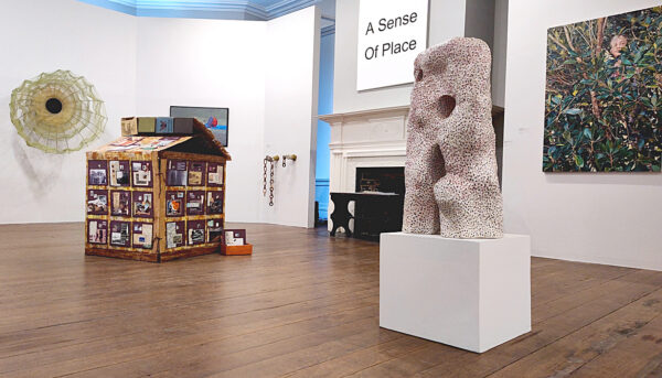 Two and 3 dimensional artworks displayed in a high ceilinged gallery with white walls.