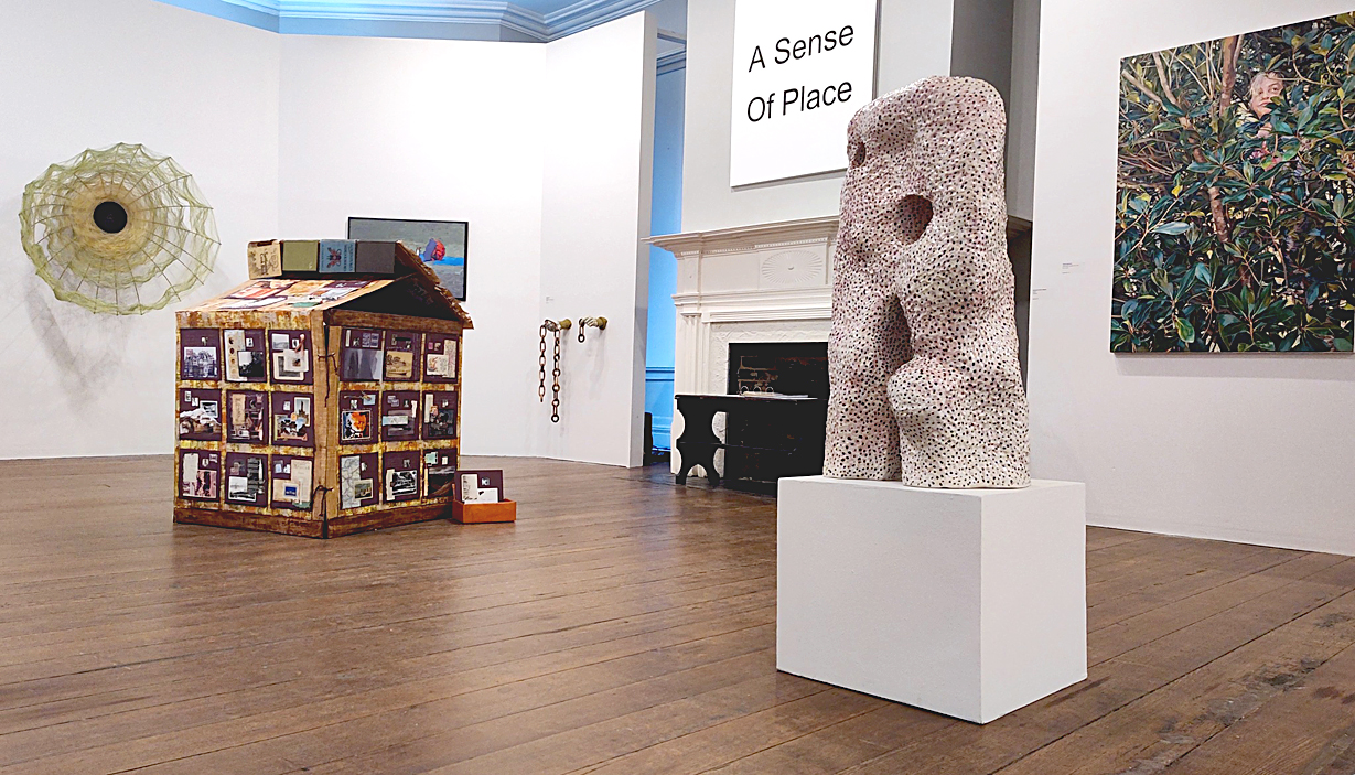 Two and 3 dimensional artworks displayed in a high ceilinged gallery with white walls.