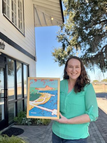 A woman with long dark hair smiles warmly as she holds a painting for viewing, outside a gallery.
