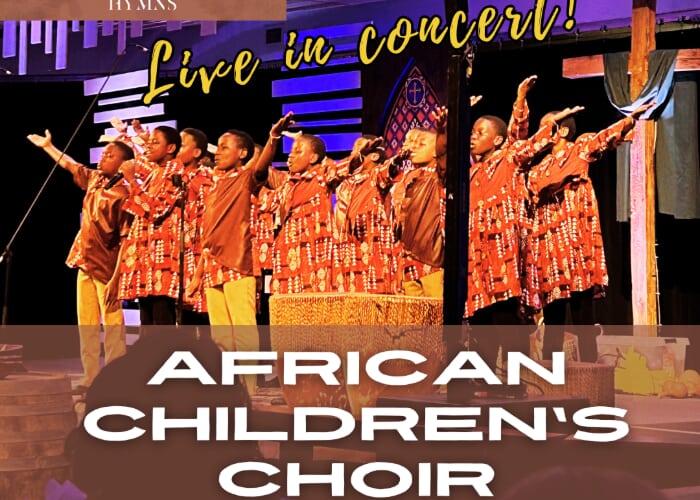 A choir of about a dozen Black youth perform onstage. They wear traditional African attire.