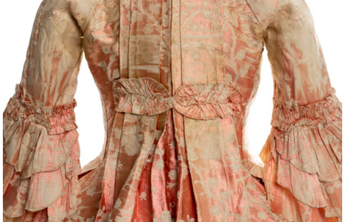 An antique gown of luxurious peach fabric, hand-embroidered and with many embellishments.