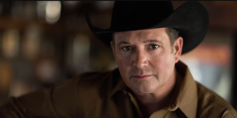 Close-up of a man in a black cowboy hat looking intently at the viewer.